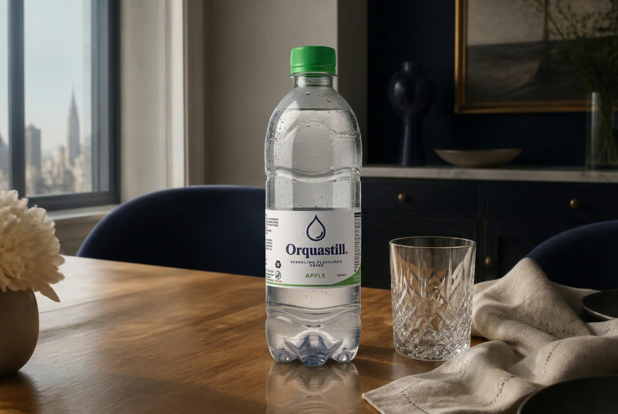 An Orquastill bottle and cut-crystal tumbler on an oak dining table